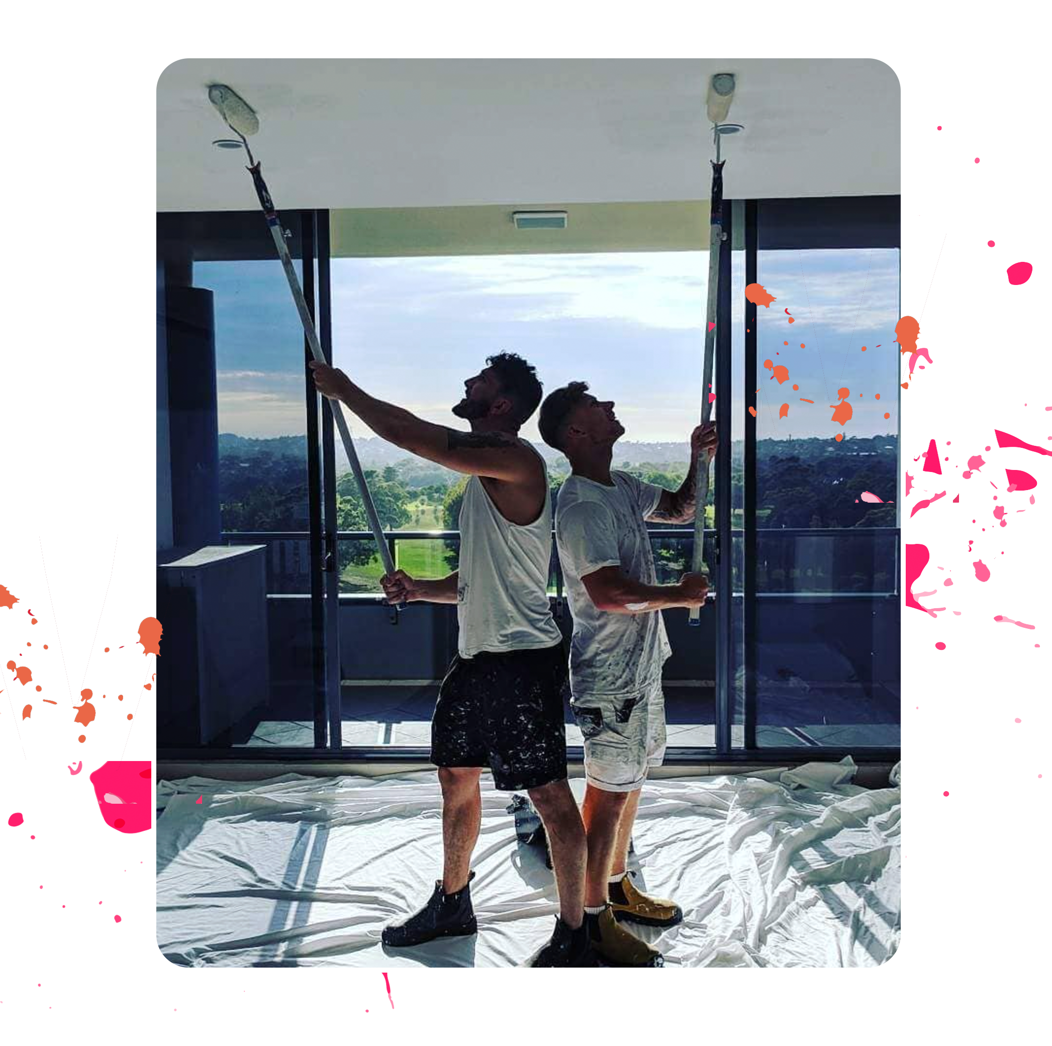 Two professional decorators standing back to back using roller brushes during a painting job