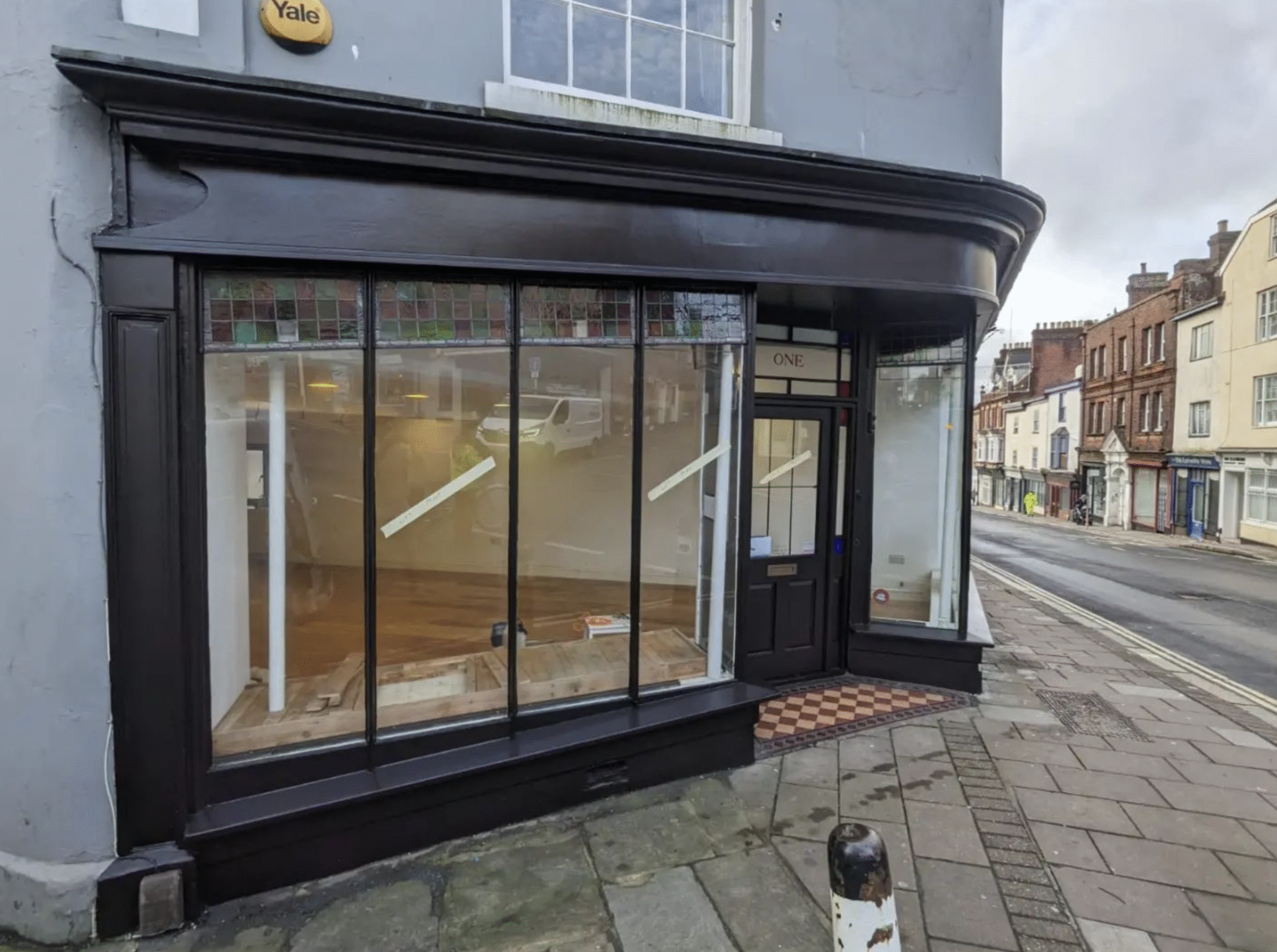 Side-angle view of a freshly painted shopfront showing newly decorated window frames and exterior detailing
