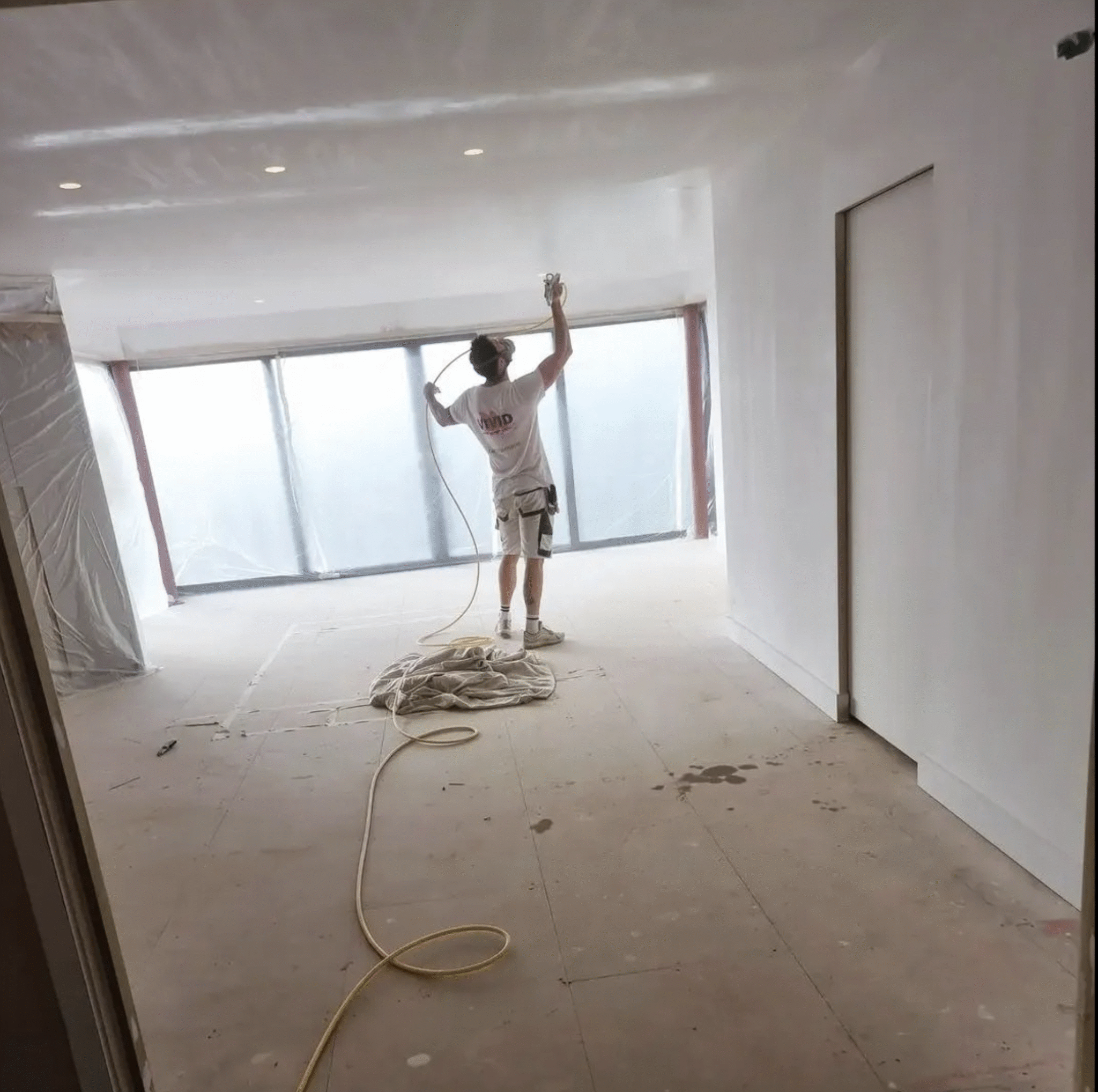 Decorator painting inside an industrial room mid-way through a commercial redecoration project in Exeter